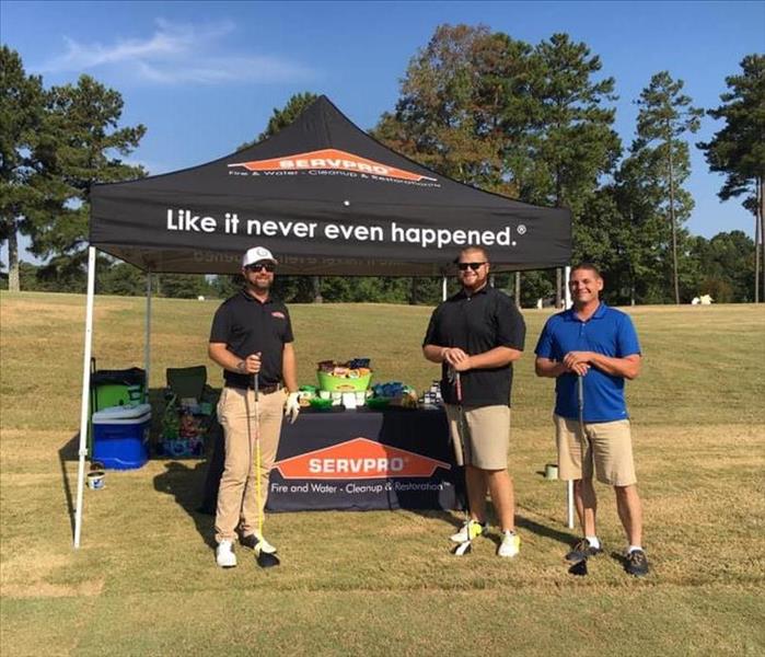 Three guys standing in front of our SERVPRO tent at a golf tournament 